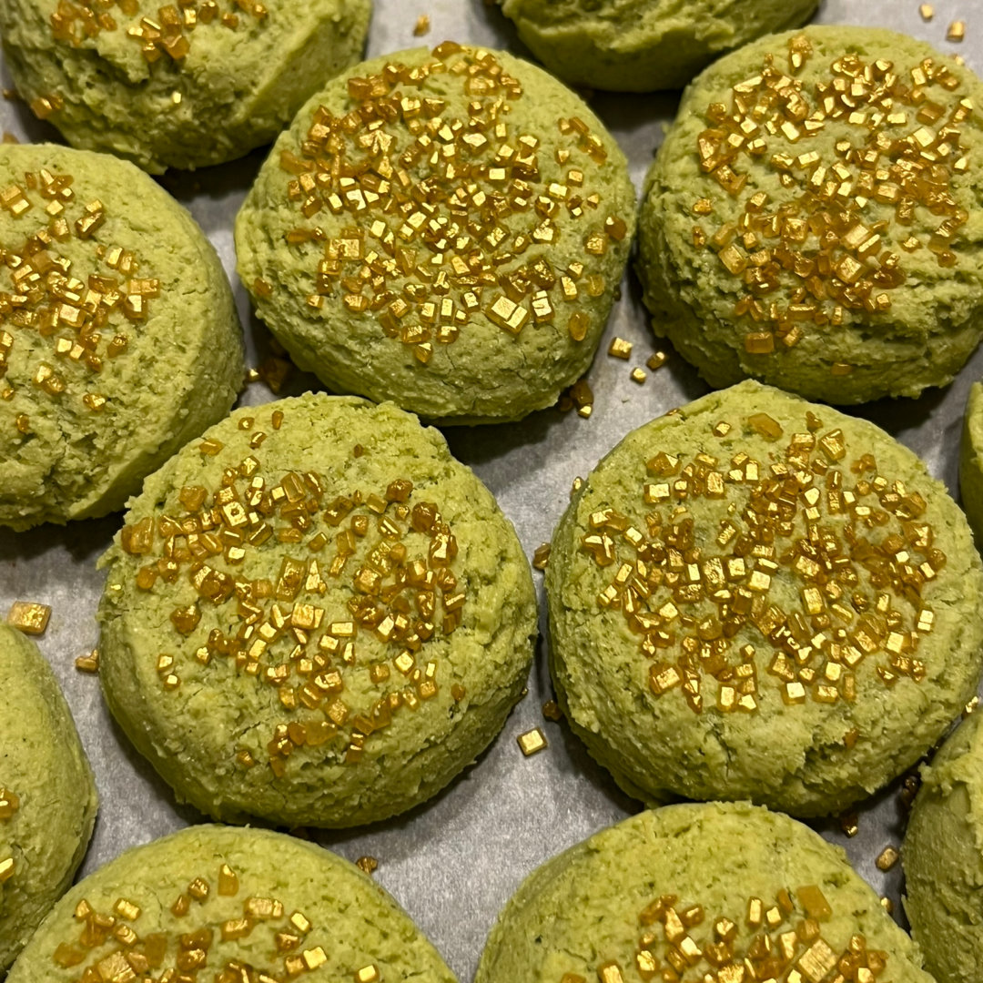 Cilantro and Lime cookies: green cookies with gold sugar sprinkles on a white parchment paper background