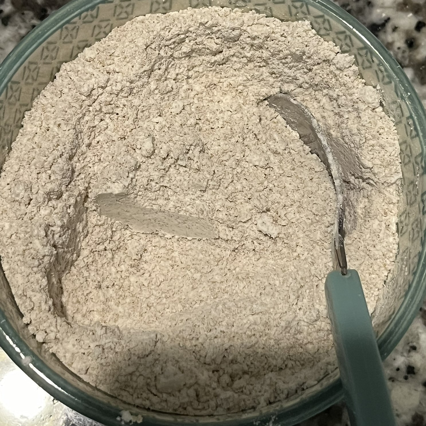 small, green and white ceramic bowl with flour, brown sugar, baking soda, and salt stirred together to a consistent texture