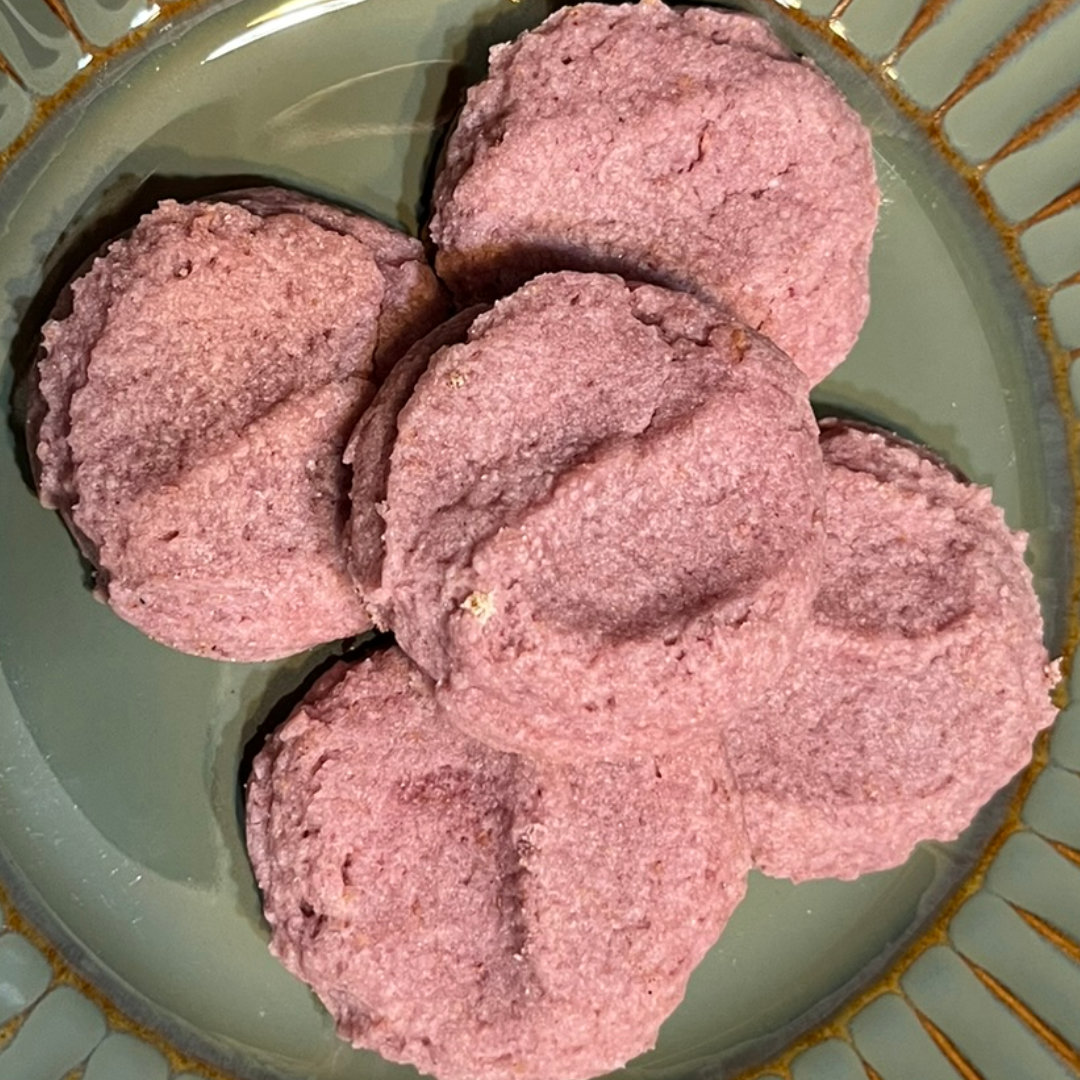 pile of pink Raspberry Lemonade Cookies on a green plate with a ridged starburst pattern around the rim