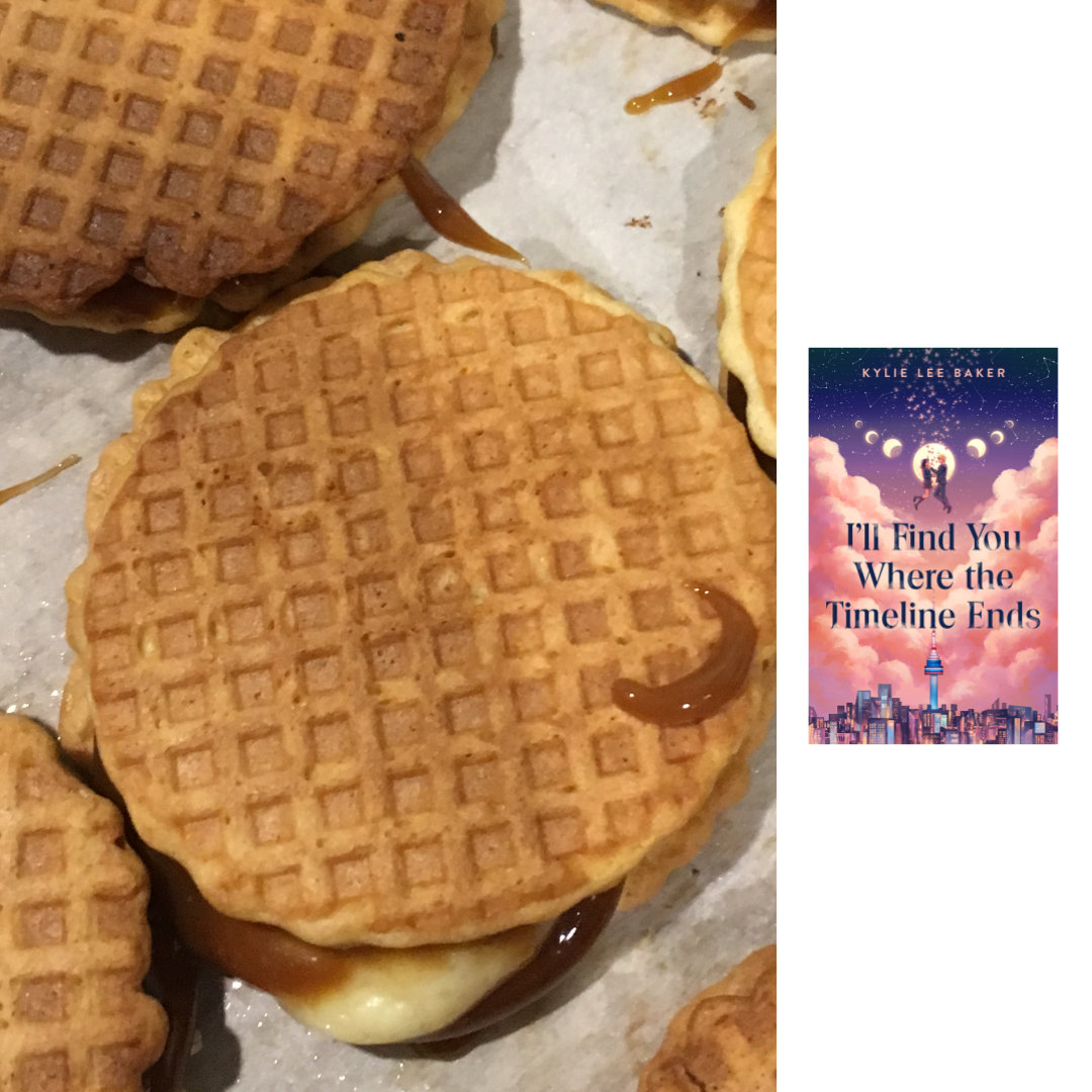 photo of a close-up of Cheesecake Stroopwafel Cookies: 2 thin, vanilla waffle cone wafers with caramel and cheesecake filling sandwiched in between. The cookies are sitting close together on top of a sheet of parchment paper, and the caramel and cheesecake fillings are peeking out from between the wafers of each cookie sandwich. To the right of the cookies, against a white background, is the cover of I'LL FIND YOU WHERE THE TIMELINE ENDS by Kylie Lee Baker - There's an illustration of a cityscape at the bottom of the image, with a tall, blue, white, and red tower in the center like a beacon. Above the cityscape is a layer of billowy, pink clouds behind the title, written in bold, serif text. The clouds open up to a starscape above them, including a moon in all its phases. The full moon is in the center, around the figures of a boy and a girl, who appear to be floating in the sky above the clouds. The waxing and waning phases of the moon are shown in progressively smaller circles to the right and left of the full moon, in a bit of a V shape.