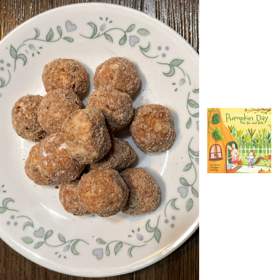 photo of Pumpkin Spice Teacakes cookies. A pile of bite-sized, spherical cookies dusted in a mixture of powdered sugar and spices sits on a small, white plate with a green and blue floral border motif. To the right of the photo of the cookies, against a white background, is a small image of the cover of PUMPKIN DAY FOR BOO AND BELLE by Laura Sassi and Farah Shah. A small rabbit, wearing a pink sweater and red skirt, stands in the doorway of her home, which is carved out of a pumpkin. Her friend, a chipmunk wearing a blue jacket, is walking up the sidewalk to greet her. There are multiple small pumpkins lining the sidewalk, and a field full of large squash blossoms, of a similar size to the pumpkin that makes Belle's house, in the background. The title is written in green across a yellow sky.