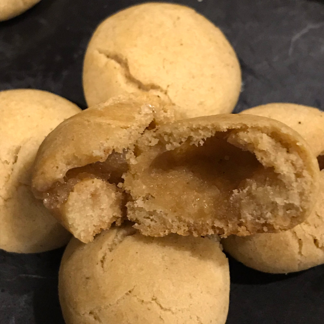 A cropped, close-up photo of Fall Phantoms Cookies, which are bite-sized maple cookies with a hollow center, on a black plate.