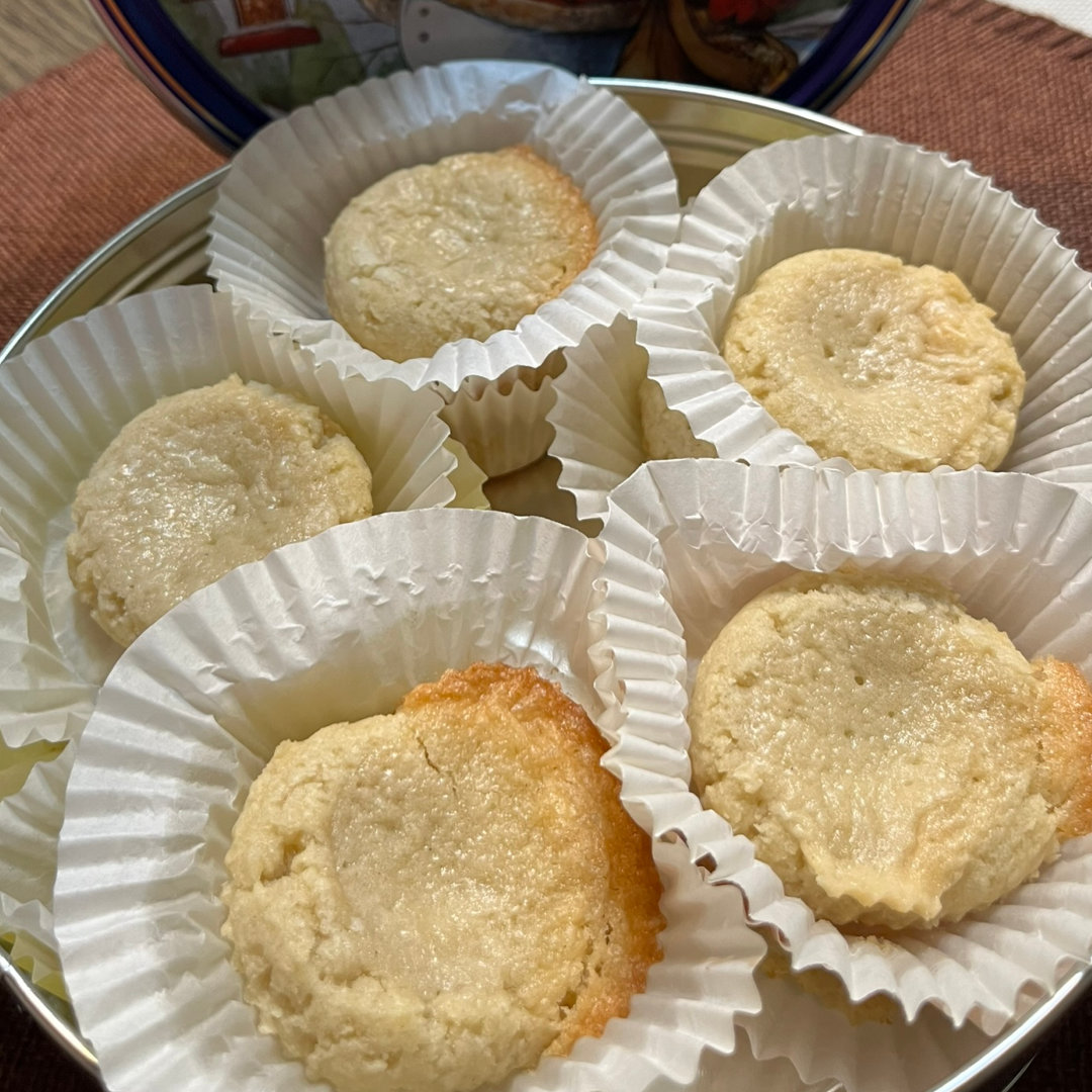 close-up photo of Gooey Butter Cookies in white cupcake wrappers. Soft butter cookies, golden around the edges, topped with a layer of gooey, sweet, buttery custard-like filling.