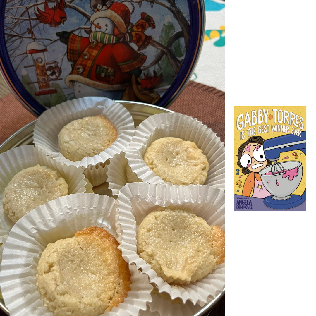 close-up photo of Gooey Butter Cookies in white cupcake wrappers, arranged inside a snowman cookie tin. Soft butter cookies, golden around the edges, topped with a layer of gooey, sweet, buttery custard-like filling. To the right of the photo, against a white background is the illustrated cover of GABBY TORRES IS THE BEST WINNER EVER by Angela Dominguez. A cartoon-ish drawing of a girl with short, curly, brown hair and large glasses, wearing an orange shirt and a pink apron is mixing something pink in a large, blue stand mixer. There are pink splatters on her shirt, forehead, and glasses. She has a worried grimace on her face as she watches the mixer do its work.