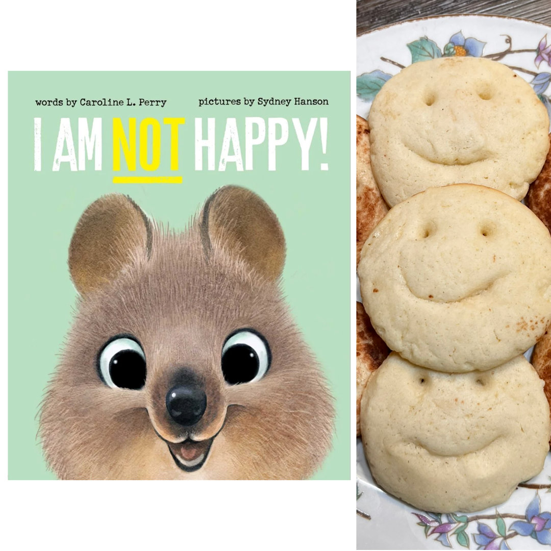 Cover for I AM NOT HAPPY by Caroline L. Perry and illustrated by Sydney Hanson. Close-up illustration of the face of a smiling quokka, with its adorable, big, bright eyes and puffy cheeks, against a teal background, with the title in bold, all-caps block text across the top. To the right of the book cover is a close-up cropped photo of a plate full of Happy Smile Sugar Cookies - Three sugar cookies with happy faces carved into them.